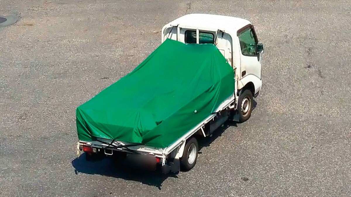 鮮やかな緑色の軽量帆布トラックシートがトラック荷台に広げられているイメージ